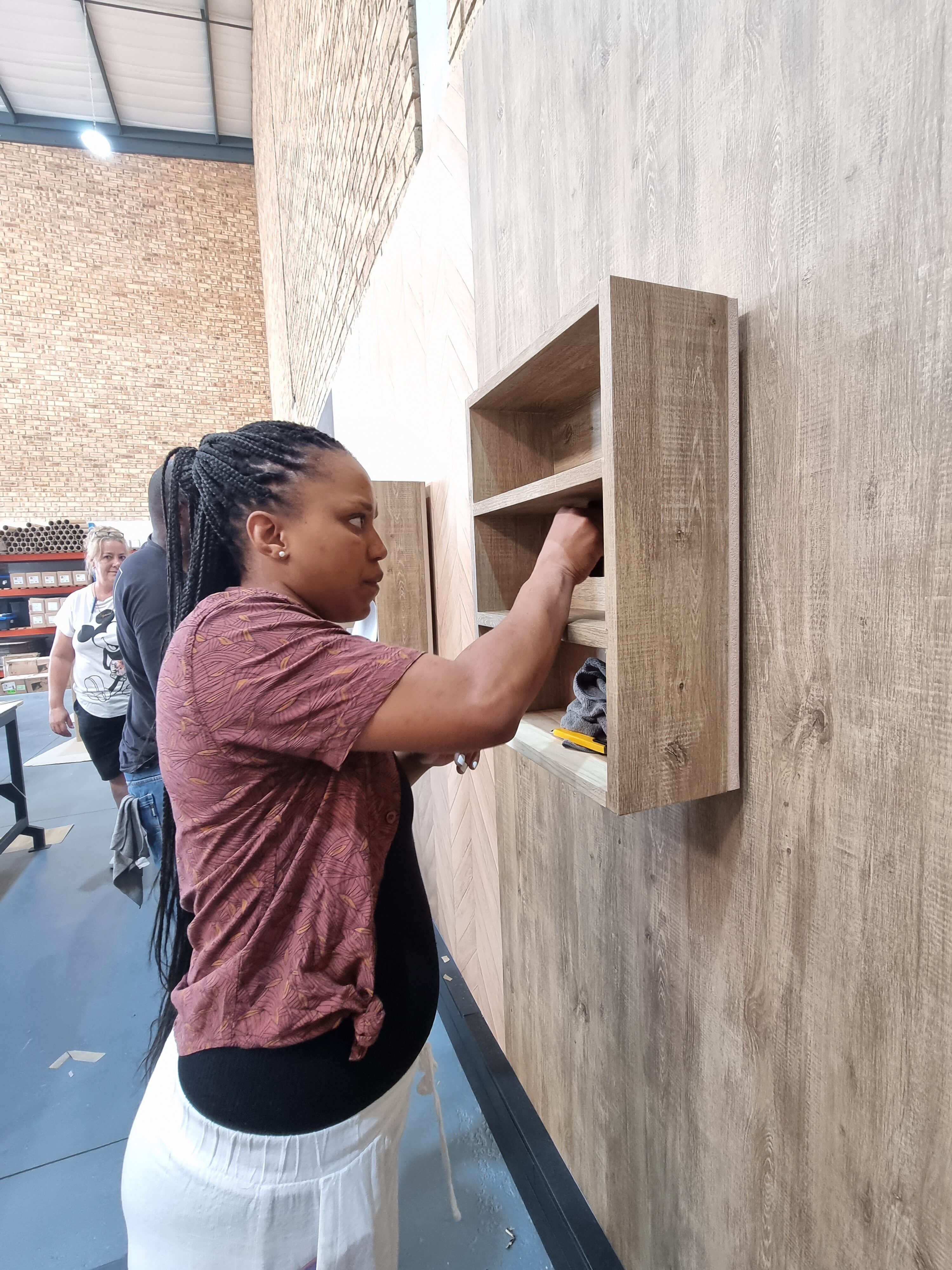 Applying Cover Styl' film to a wall-mounted shelf during training